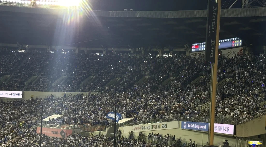 Fans waving phone lights under the night scoreboard at Jamsil Baseball Stadium during HanBuddy Run 1